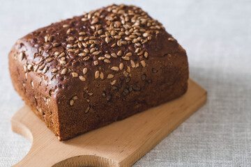 Fresh delicious whole grain rye bread with seeds close-up. Freshly baked bread on a wooden board. The context of a bakery with delicious bread. Confectionery products.