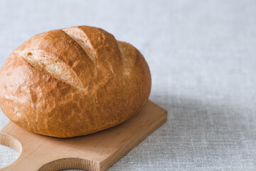 Fresh delicious bread close-up. Freshly baked sourdough bread with a golden crust on a wooden board. The context of a bakery with delicious bread. Confectionery products.
