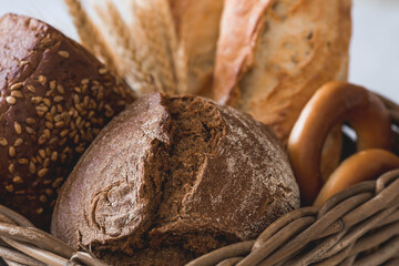 Assortment of fresh bread in a wicker basket close-up. Freshly baked bread on the table. The context of a bakery with delicious bread. Confectionery products.