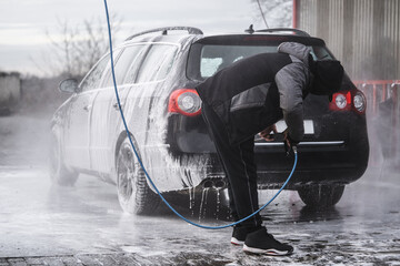 the car at the car wash is covered with foam, wash under pressure with a stream of water