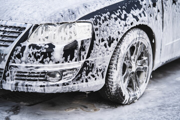 the car at the car wash is covered with foam, wash under pressure with a stream of water