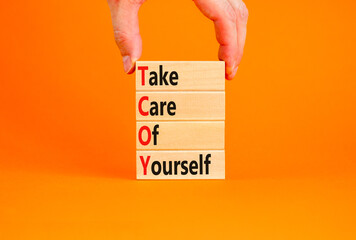 TCOY take care of yourself symbol. Concept words TCOY take care of yourself on wooden block on beautiful orange table orange background. Business TCOY take care of yourself concept. Copy space.
