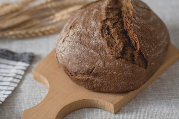 Fresh delicious bread close-up. Freshly baked sourdough bread with a golden crust on a wooden board. The context of a bakery with delicious bread. Confectionery products.