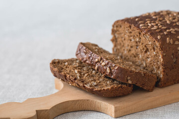 Fresh delicious whole grain rye bread with seeds close-up. Freshly baked bread on a wooden board. The context of a bakery with delicious bread. Confectionery products.