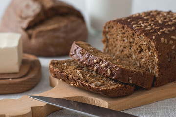 Fresh delicious whole grain rye bread with seeds close-up. Freshly baked bread on a wooden board. The context of a bakery with delicious bread. Confectionery products.