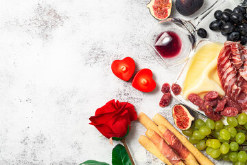 Valentine background with antipasto delicatessen snacks and wine. Grape, figs, cheese, bread stick,...