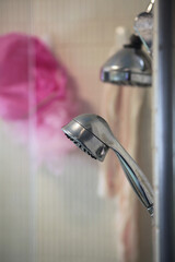 Authentic shower close up with showerhead and pink sponge washcloths. Selective focus, vertical orientation