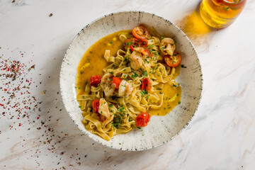 Pasta fettuccine with shrimps and tomatoes on marble table top view