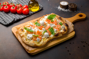 Pizza with salmon and cheese on Roman dough on dark brown table