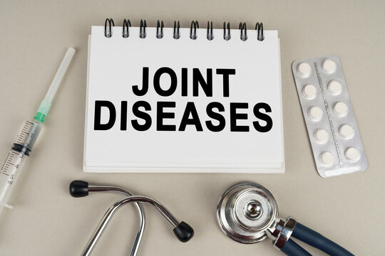On a gray surface there is a syringe, a stethoscope and a notepad with the inscription - joint diseases