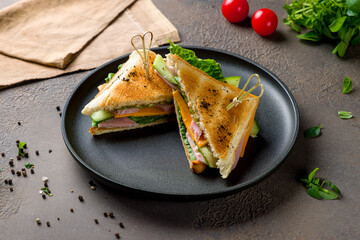 ham and cheese sandwich on black plate on brown table