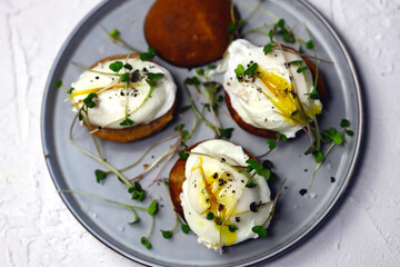 Poached eggs with microgreens on a crispy bun on a plate.