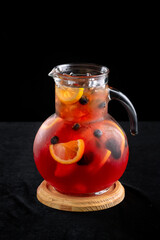 Glass carafe of cold lemonade, on a black background