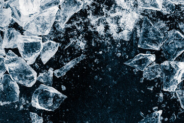 Ice cubes and crushed ice pieces on black background. Chill backdrop.
