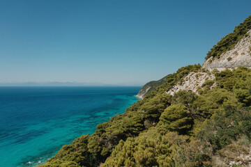 Seascape and sandy beach with turquoise clear waters and trees in Greece