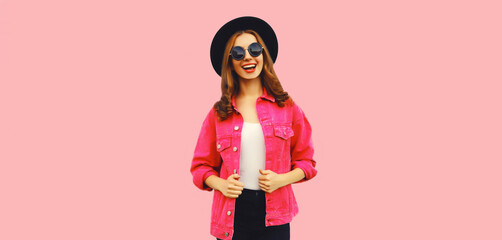 Portrait of stylish modern smiling young woman wearing jacket, black round hat on pink background, blank copy space for advertising text