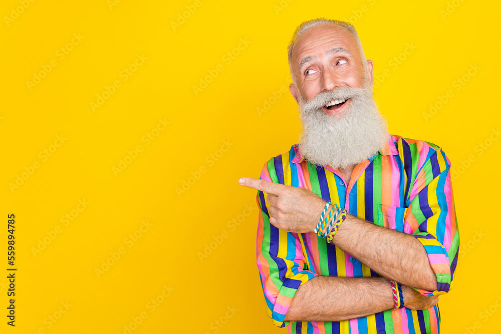 Poster Portrait of cheerful nice granddad toothy smile look indicate finger empty space isolated on yellow color background