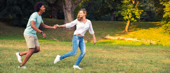Young happy couple running and playing in the park in spring