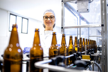 Portrait of female factory supervisor controlling beer production in alcohol beverage bottling...