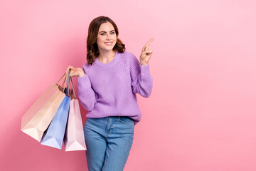 Photo of adorable charming girl dressed purple pullover rising bargains pointing empty space isolated pink color background