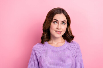 Portrait of optimistic thoughtful girl curly hairdo wear violet pullover look empty space biting lip isolated on pink color background