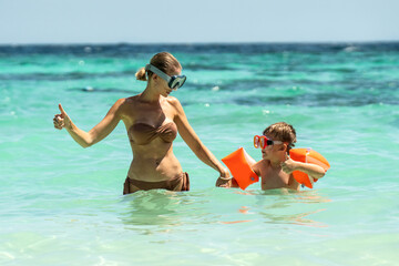 Photo of happy mother and her little son snorkeling on tropical beach, having fun together. Hobby....