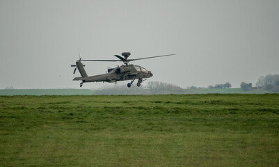 dark grey helicopter hovering low above a field