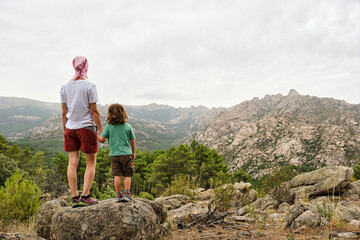 A Woman in headscarf fights cancer in the wilderness with child by hand