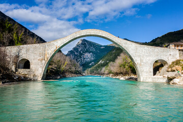 The great arched stone bridge of Plaka on Arachthos river, Tzoumerka, Greece. - 559907578