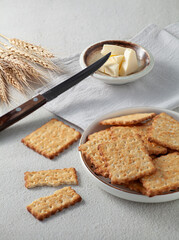 Plate of Dry thin crispy crackers with saucer of butter and knife on the table. Selective focus