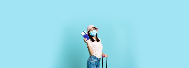 Fototapeta na wymiar Full length of happy asian girl tourist, woman on vacation standing with suitcase, showing tickets and passport, travelling abroad, blue background