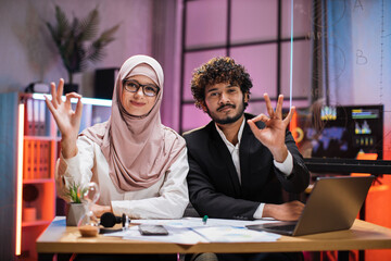 Confident two multi ethnic economists, young experienced muslim female and businessman, office...