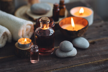 Obraz na płótnie Canvas Concept of natural essential organic oils, Bali spa, beauty treatment, relax time. Atmosphere of relaxation, pleasure. Candles, towels, dark wooden background. Alternative oriental medicine