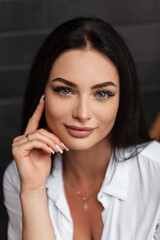 Fashionable beautiful woman with blue eyes and a clean face in a fashion white shirt on a dark background in the city