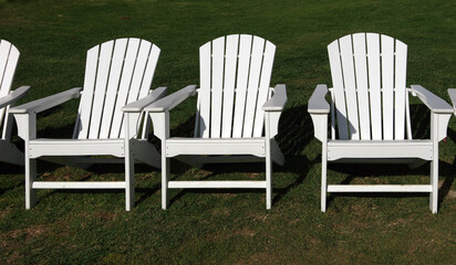 Row of white Adirondack chairs on the lawn