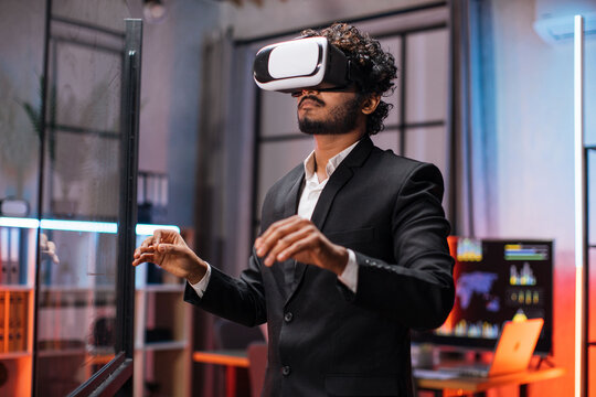 Business man in VR glasses standing at office room and gesturing with hands. Young male company worker having briefing with modern technology. Concept of people and augmented reality.