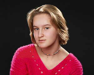 a high school student  is posing for actor headshots for a musical. The girl has short blond hair and wears a pink sweater.