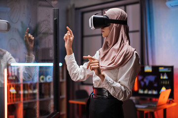 Young female company workers wearing VR headset while having meeting at office room. Confident muslim woman in hijab using innovative technology during business strategy.