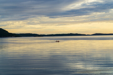 Two kayakers in the light of the sunset on a fjord on the Atlantic coast in Norway