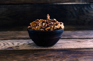 Peeled walnuts in an earthenware dish on a kitchen wooden table