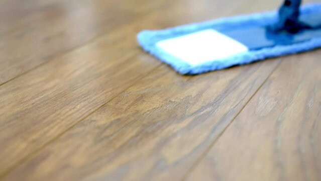 a woman cleans and mops the floor in the living room. The woman does housework.