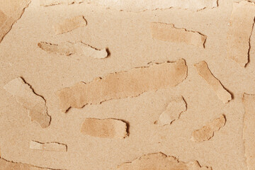 Ripped pieces craft paper on natural brown cardboard background. Texture