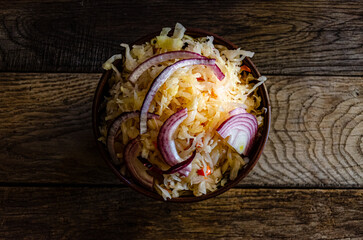 Sauerkraut in earthenware on a wooden background. Cooking homemade fermented food.