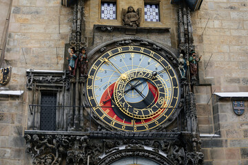 Prague, Czech Republic, 15 December 2022: Old town square with snow at sunny winter day, town hall tower with Astronomical clock Orloj, narrow street, Christmas time, ancient figures flanking clock