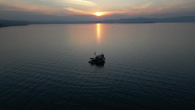Fishing boat trawler ship sailing on sea after sunset aerial shot. High quality 4k footage