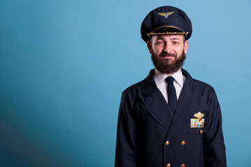 Smiling airplane pilot wearing uniform and hat front view portrait, plane captain looking at...