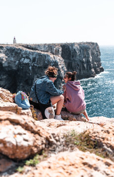 Pareja de chicas observando el mar desde un acantilado en cabo de San Vicente. 