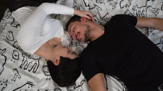 The young couple in love are lying on the bed. Beautiful couple exchange caresses and kisses. Love concept.
