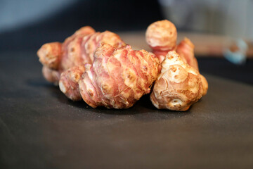 Unpeeled and raw Jerusalem artichokes or Topinambur on a table