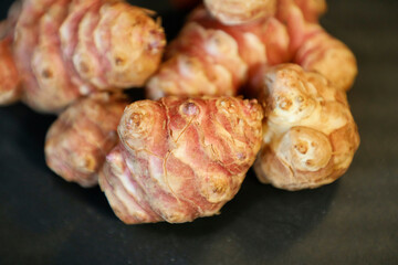Unpeeled and raw Jerusalem artichokes or Topinambur on a table